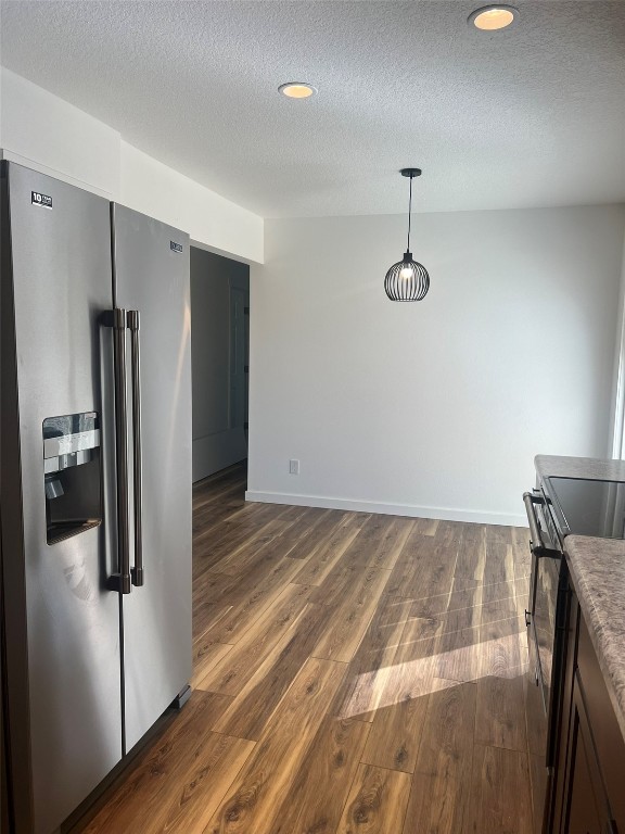 kitchen with pendant lighting, stainless steel appliances, a textured ceiling, and dark hardwood / wood-style flooring