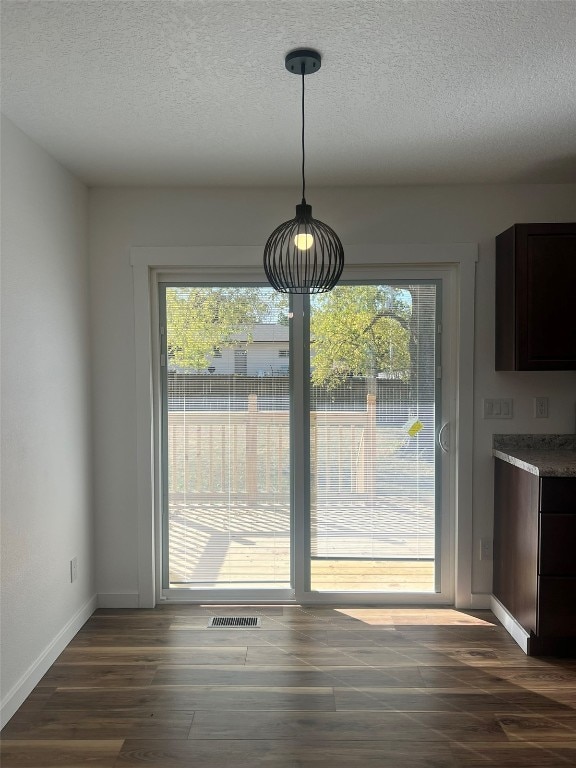 unfurnished dining area with a textured ceiling, dark hardwood / wood-style floors, and plenty of natural light