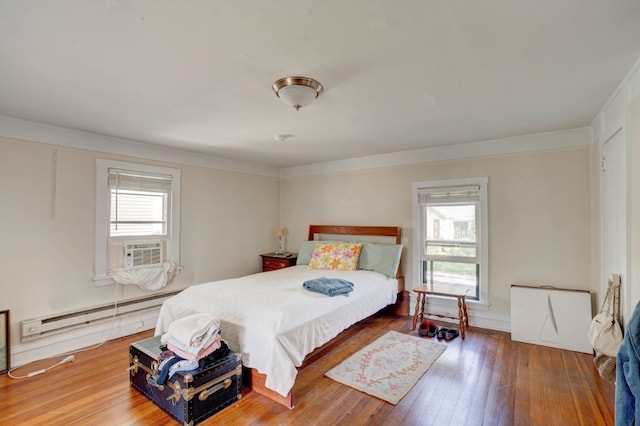 bedroom featuring wood-type flooring, a baseboard radiator, and multiple windows