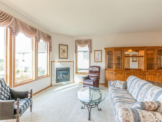 living room featuring a tile fireplace, light carpet, and baseboards