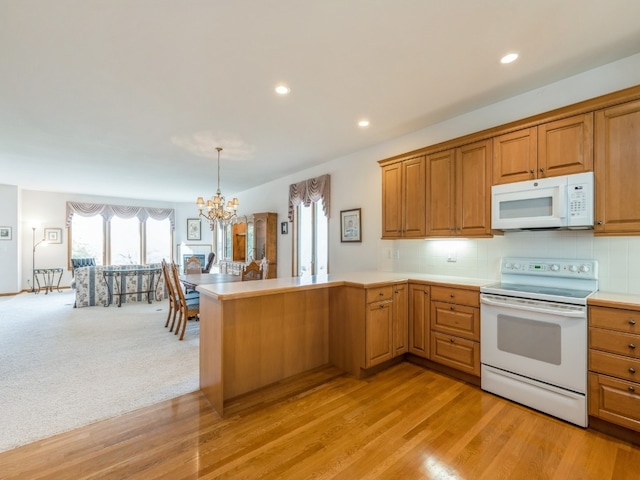 kitchen featuring decorative light fixtures, light wood-type flooring, a chandelier, white appliances, and tasteful backsplash