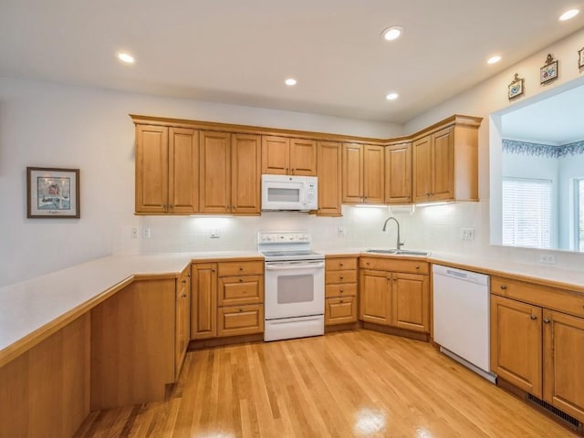 kitchen with white appliances, light countertops, a sink, and light wood finished floors