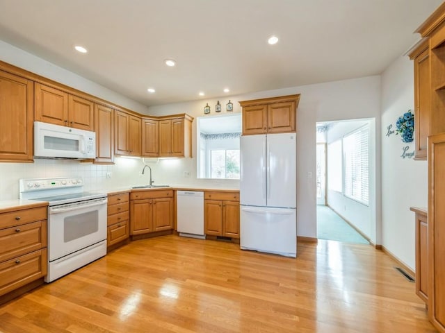 kitchen with white appliances, light wood-style flooring, light countertops, and a sink