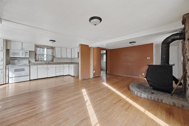 unfurnished living room featuring a textured ceiling, light hardwood / wood-style floors, a wood stove, and sink