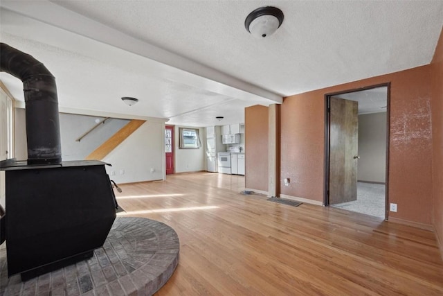 living room with beam ceiling, light hardwood / wood-style floors, and a textured ceiling