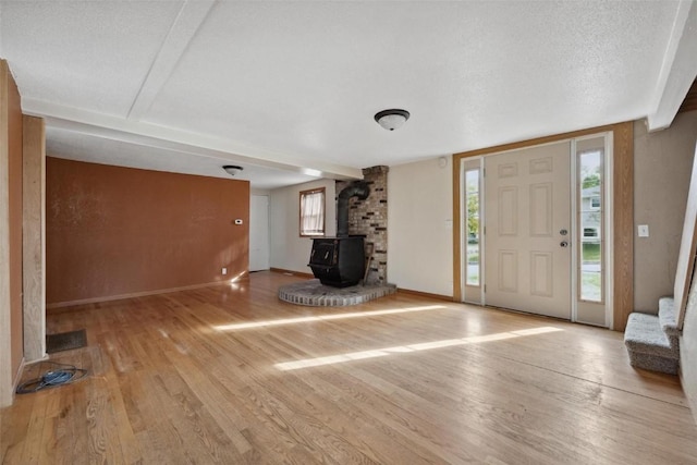 entrance foyer featuring a textured ceiling, light hardwood / wood-style flooring, and a wood stove