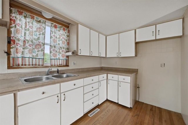 kitchen featuring light hardwood / wood-style flooring, white cabinetry, and sink