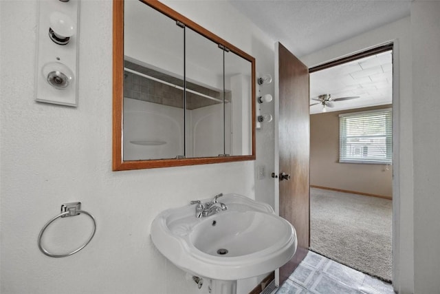 bathroom with a textured ceiling, ceiling fan, sink, and walk in shower