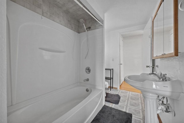 bathroom featuring tiled shower / bath combo and toilet