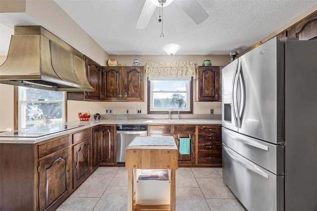 kitchen with a center island, premium range hood, sink, dark brown cabinets, and stainless steel appliances