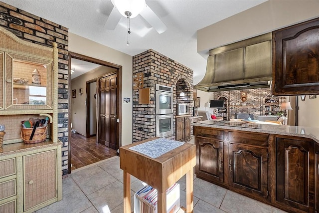 kitchen featuring dark brown cabinetry, a textured ceiling, and light tile patterned floors