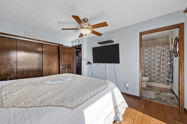 bedroom featuring hardwood / wood-style floors, ceiling fan, a closet, and ensuite bath