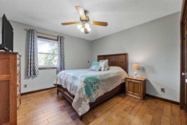 bedroom with a textured ceiling, hardwood / wood-style flooring, and ceiling fan