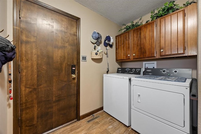 laundry area featuring washer and dryer, a textured ceiling, light hardwood / wood-style floors, and cabinets