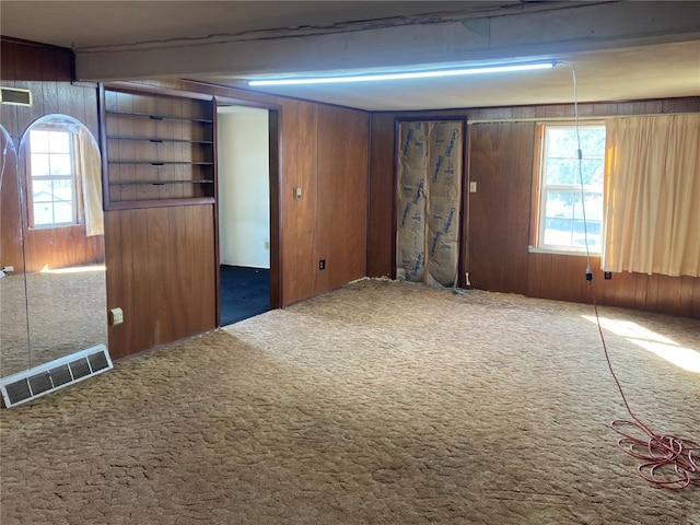 interior space featuring wood walls, beam ceiling, and carpet