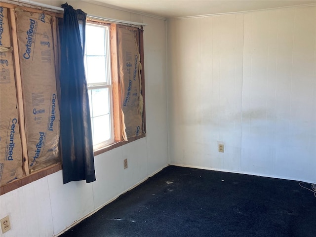 spare room featuring dark colored carpet and a healthy amount of sunlight