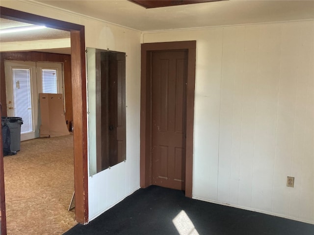 carpeted empty room featuring wooden walls