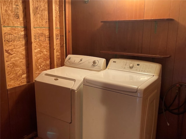 clothes washing area featuring wooden walls and independent washer and dryer