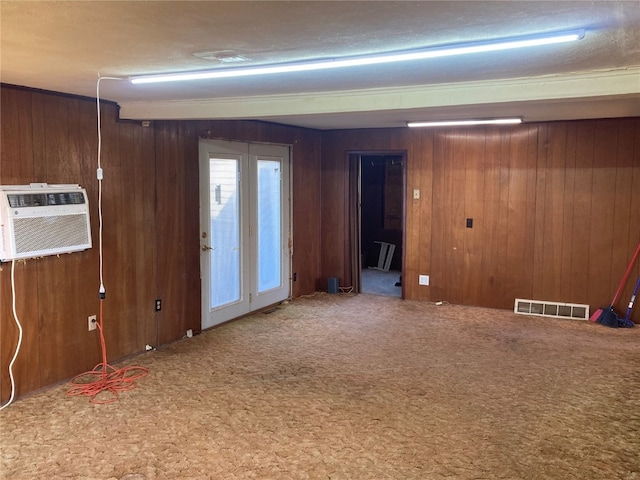 interior space with wood walls, carpet flooring, and an AC wall unit