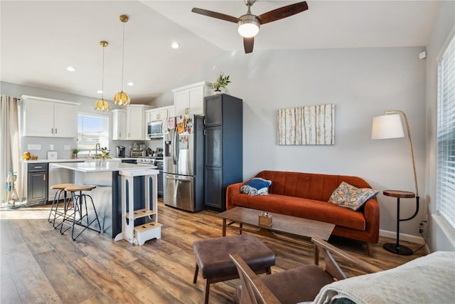 living room featuring vaulted ceiling, light wood-type flooring, and ceiling fan