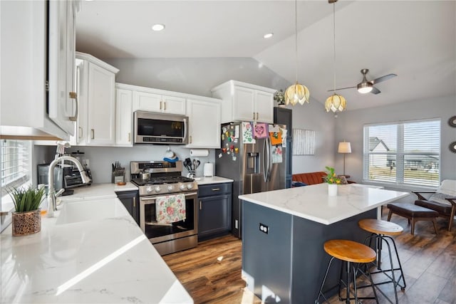 kitchen with white cabinetry, stainless steel appliances, decorative light fixtures, and a kitchen island