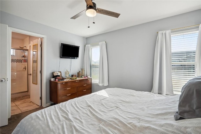 bedroom with multiple windows, dark colored carpet, ceiling fan, and ensuite bathroom