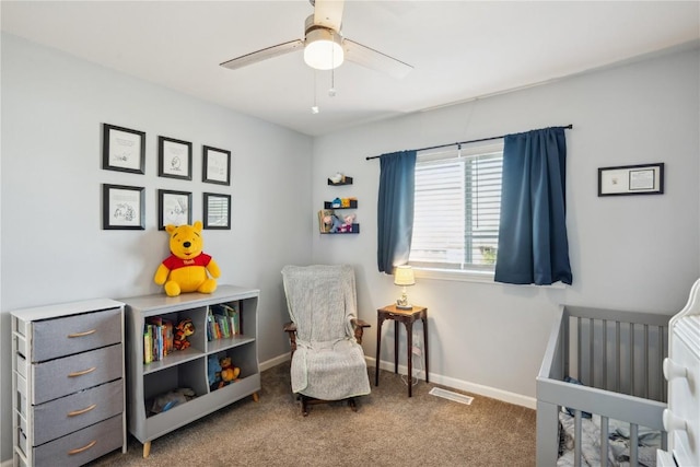 carpeted bedroom featuring a nursery area and ceiling fan