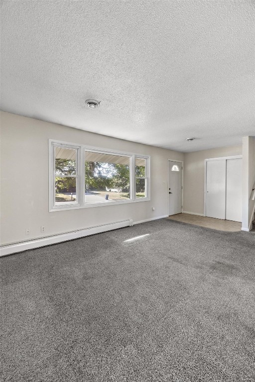 unfurnished room with a textured ceiling, carpet, and a baseboard heating unit