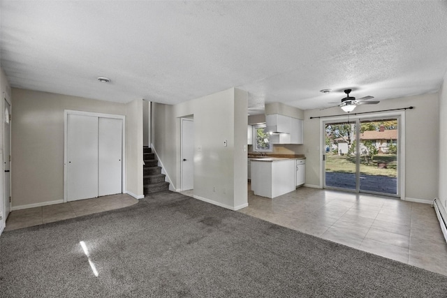 unfurnished living room with ceiling fan, light colored carpet, sink, and a textured ceiling