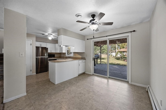 kitchen featuring stainless steel refrigerator, a baseboard heating unit, a textured ceiling, and white cabinetry