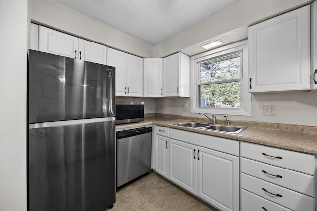 kitchen with white cabinets, light tile patterned floors, sink, a textured ceiling, and appliances with stainless steel finishes