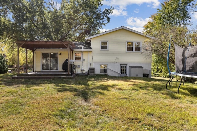 rear view of house with a trampoline, central AC, and a lawn