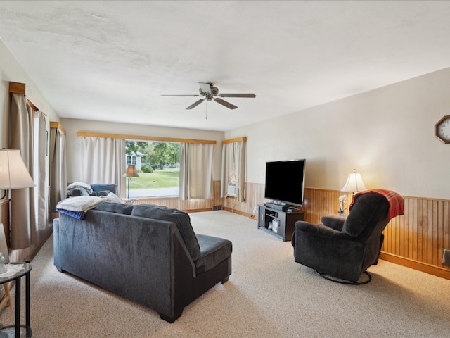 carpeted living room featuring ceiling fan and wood walls