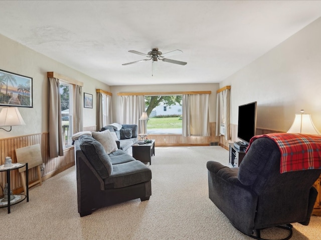 carpeted living room featuring plenty of natural light, wooden walls, and ceiling fan