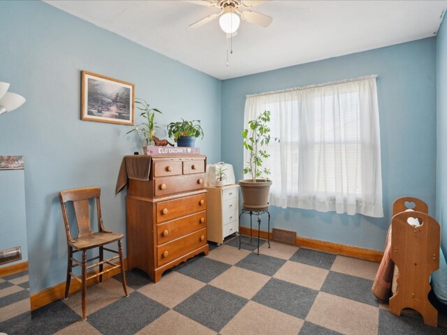 living area featuring dark carpet and ceiling fan