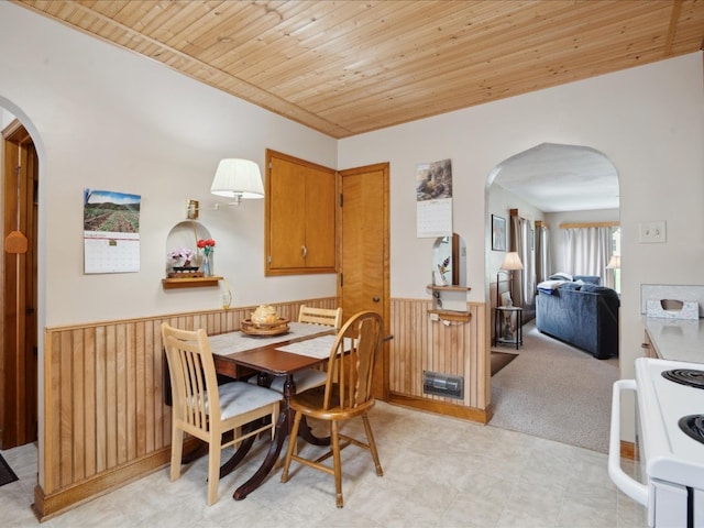 carpeted dining area featuring wood walls and wooden ceiling