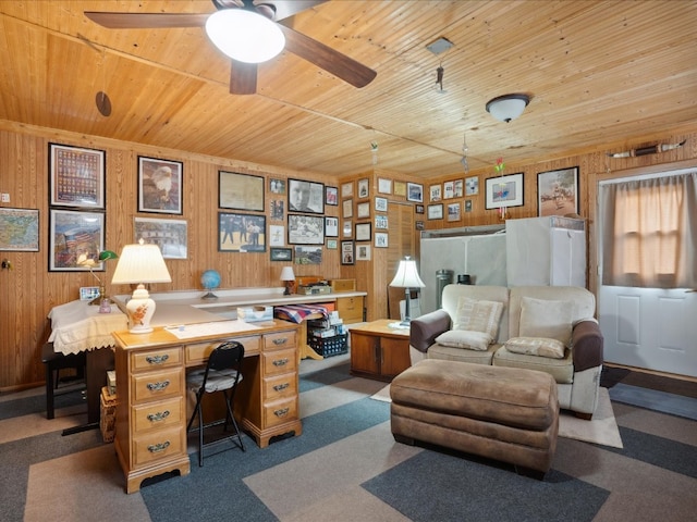 office featuring wood walls, wooden ceiling, dark colored carpet, and ceiling fan