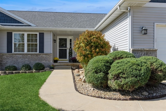 entrance to property with a garage and a lawn