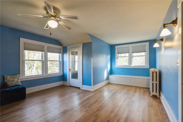 empty room with radiator, ceiling fan, wood-type flooring, and lofted ceiling