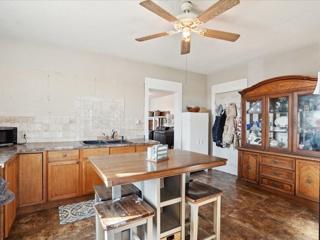 kitchen featuring ceiling fan, tasteful backsplash, light stone countertops, and sink