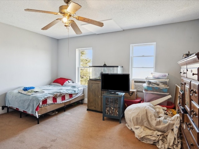 bedroom with a textured ceiling, light carpet, multiple windows, and ceiling fan