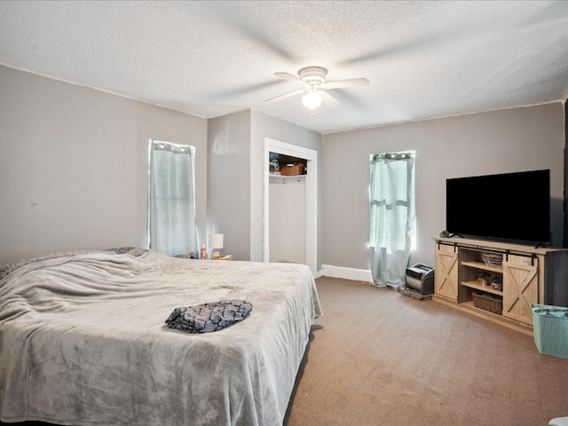 bedroom featuring a textured ceiling, light colored carpet, and ceiling fan