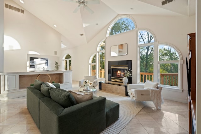 living room featuring high vaulted ceiling, ceiling fan, a fireplace, and light tile patterned floors