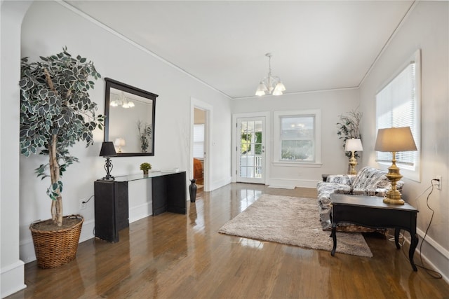 sitting room with plenty of natural light, dark hardwood / wood-style floors, crown molding, and a notable chandelier