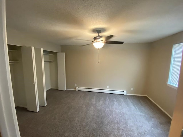 unfurnished bedroom featuring ceiling fan, multiple closets, a baseboard radiator, and dark carpet