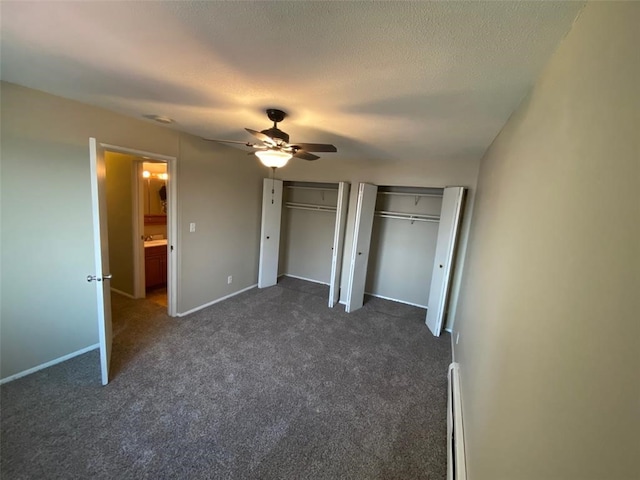 unfurnished bedroom with ceiling fan, a textured ceiling, dark colored carpet, multiple closets, and a baseboard radiator