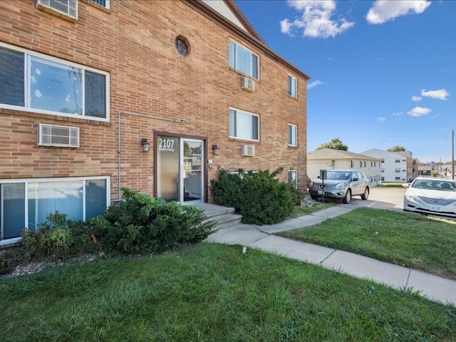 view of front of property with a front lawn and a wall unit AC