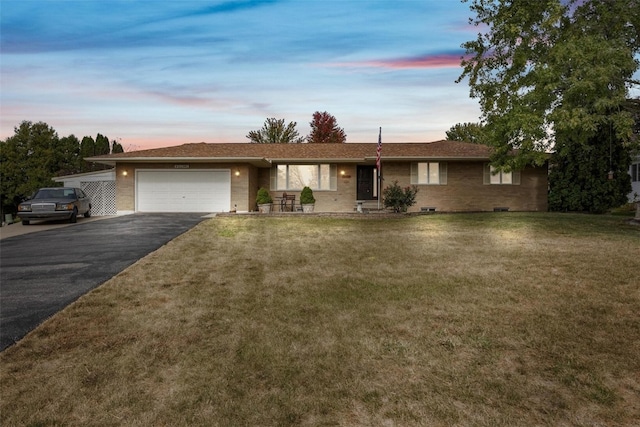 single story home featuring a garage and a lawn