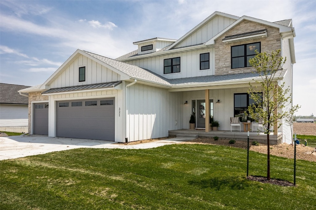 view of front of property with a garage, covered porch, and a front yard