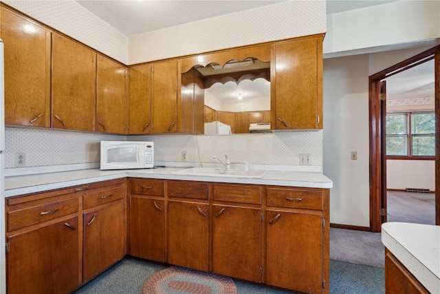 kitchen featuring dark colored carpet, sink, and tasteful backsplash